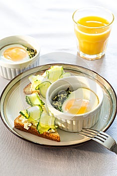 Shirred eggs Oeuf cocotte or baked eggs. healthy breakfast with eggs and spinach and toast with cucumber
