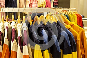 Shirt and pant hanging on hangers on a clothing rack and arranged in shelf in a modern clothe store