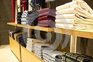 Shirt and pant hanging on hangers on a clothing rack and arranged in shelf in a modern clothe store