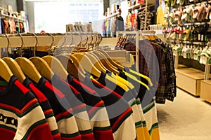 Shirt and pant hanging on hangers on a clothing rack and arranged in shelf in a modern clothe store