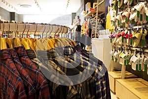 Shirt and pant hanging on hangers on a clothing rack and arranged in shelf in a modern clothe store