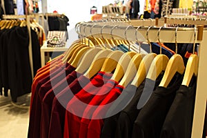 Shirt and pant hanging on hangers on a clothing rack and arranged in shelf in a modern clothe store