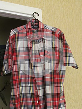 A shirt in red and white checks  on plastic hanger