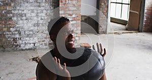 Shirtless african american man exercising with medicine ball in an empty urban building