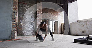 Shirtless african american man exercising with medicine ball in an empty urban building