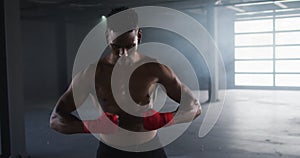 Shirtless african american man preparing hand wraps for boxing in an empty urban building