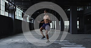 Shirtless african american man skipping the rope in an empty urban building