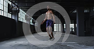 Shirtless african american man skipping the rope in an empty urban building