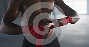 Shirtless african american man wrapping hands for boxing in an empty urban building