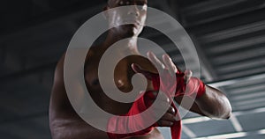 Shirtless african american man wrapping hands for boxing in an empty urban building