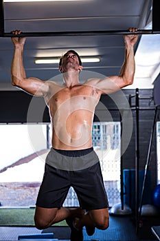 Shirtless athlete doing chin-ups