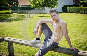 Shirtless athletic young man resting in city park