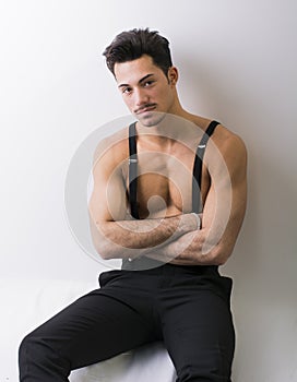 Shirtless athletic young man with suspenders and black pants