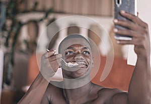 Shirtless black male holding up a spoon eating outdoors and taking a selfie