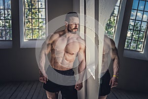 Shirtless bodybuilder posing in natural light.