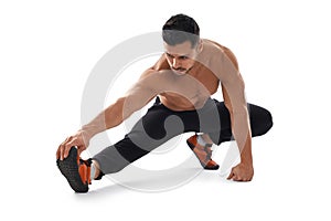 Shirtless bodybuilder stretching on floor.