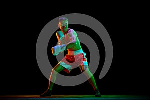 Shirtless boxer, mixed martial art fighter in gloves who preparing to fight against black mode background in mixed neon