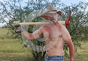 A Shirtless Cowboy Shoulders a Red Pickax