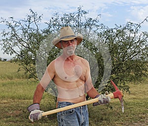 A Shirtless Cowboy Uses a Red Pickax