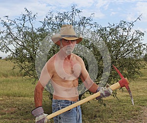 A Shirtless Cowboy Uses a Red Pickax