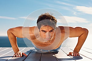 Shirtless guy doing push ups on a porch outdoors. Portrait of a healthy young masculine guy exercising on the porch.