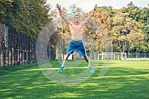 Shirtless handsome man working out in park, cross fit training. Athletic man jumping and doing exercises outdoor