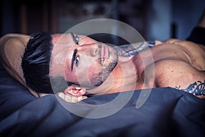 Shirtless male model lying alone on his bed