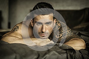 Shirtless male model lying alone on his bed