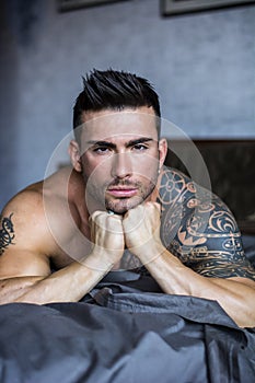 Shirtless male model lying alone on his bed