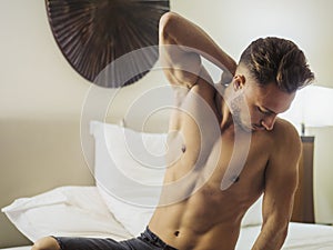 Shirtless male model lying alone on his bed