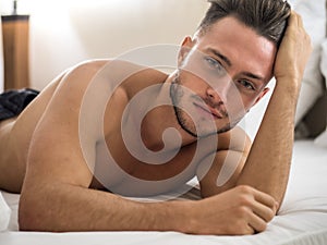 Shirtless male model lying alone on his bed