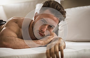 Shirtless male model lying alone on his bed