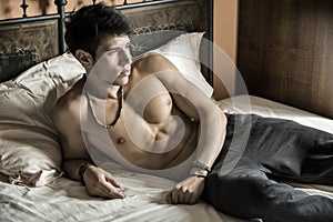 Shirtless male model lying alone on his bed