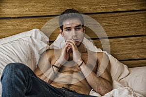 Shirtless male model lying alone on his bed