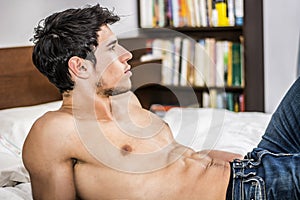 Shirtless male model lying alone on his bed