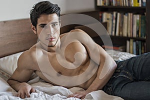 Shirtless male model lying alone on his bed