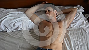 Shirtless male model lying alone on his bed