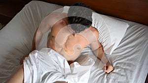 Shirtless male model lying alone on his bed