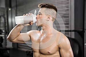 Shirtless man on bench drinking protein shake