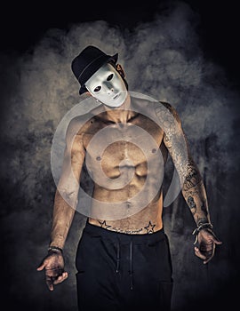 Shirtless man dancer or actor with creepy, scary mask