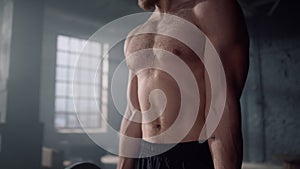 Shirtless man doing arm exercises. Athlete lifting barbell with heavy weights.