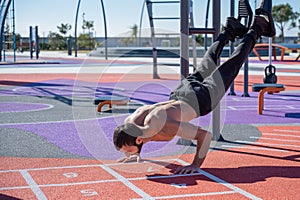 Shirtless man doing loop exercises outdoors.