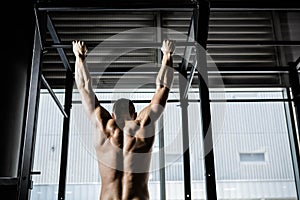 Shirtless man doing pull up photo