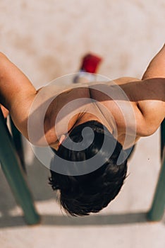 Shirtless man doing pull-ups on horizontal bar