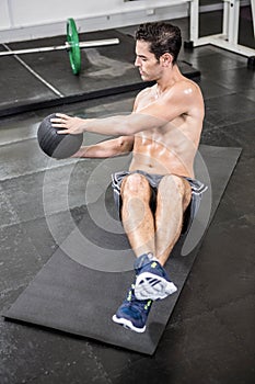 Shirtless man exercising with medicine ball