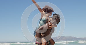 Shirtless man giving piggyback ride to woman at beach 4k