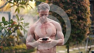 Shirtless man with muscular body uses mobile phone and sends message