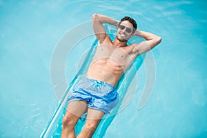 Shirtless man relaxing on inflatable raft