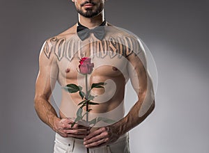 Shirtless man standing with flower