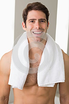 Shirtless man with towel around neck at home